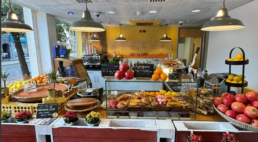 The Sip Slow counter — pastry display, fruit bowls and hanging lamps